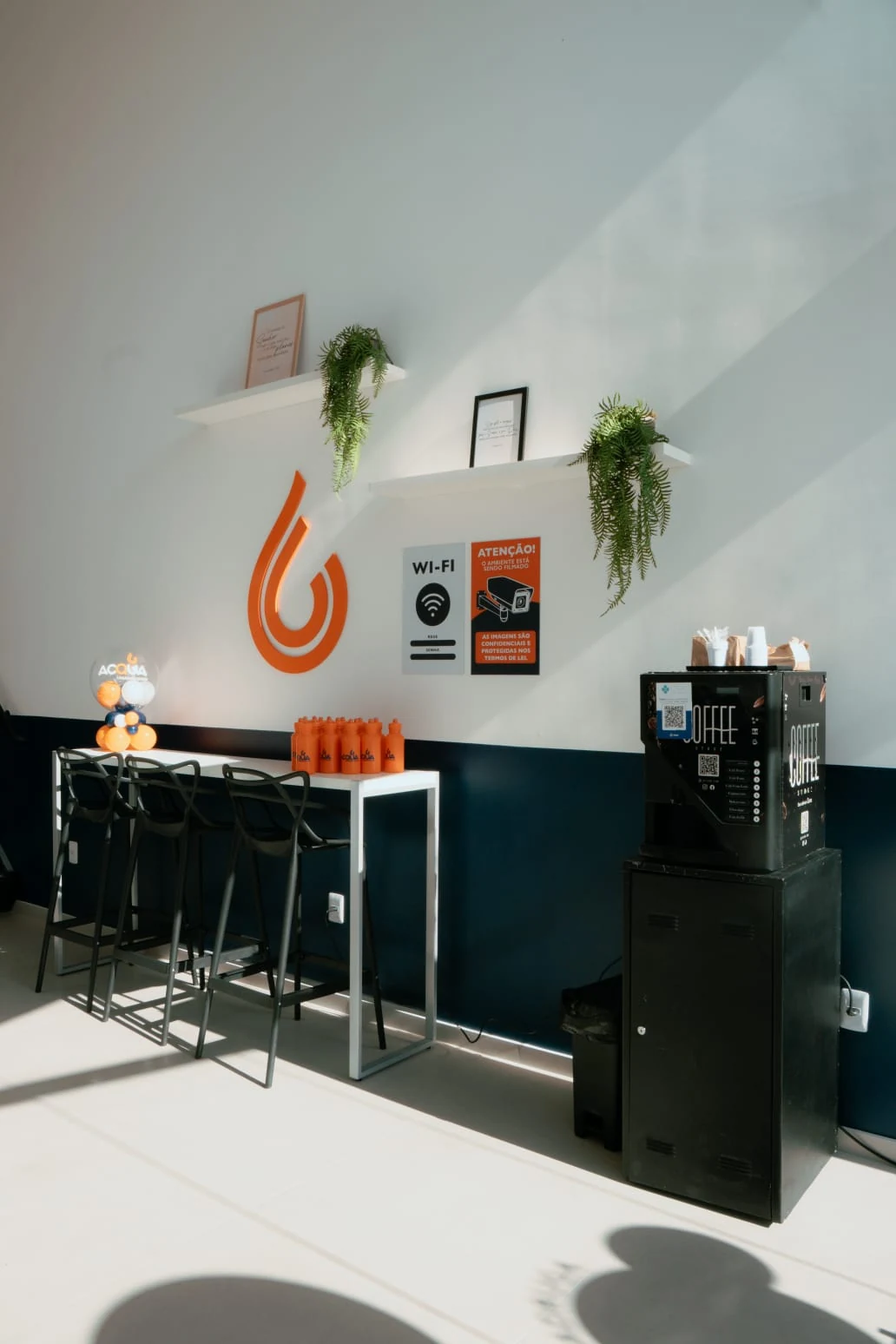 Área de espera com mesas, café e Wi-Fi na Acqua Lavanderia Express